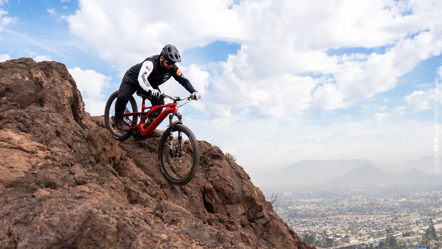 Rider descendiendo por terreno rocoso con la ciudad al fondo